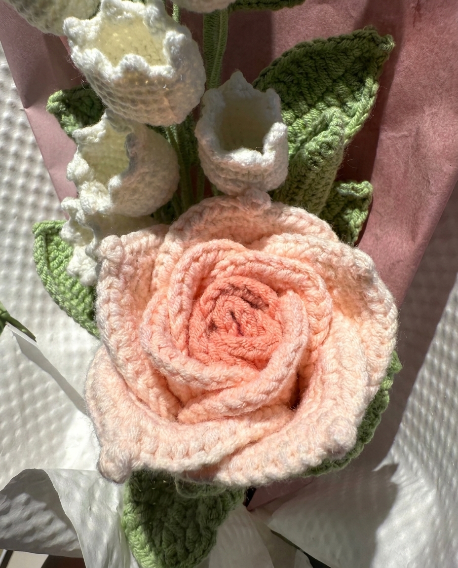 Close-up of yarn stitches and flower details on handmade pink crochet tulip and lily bouquet